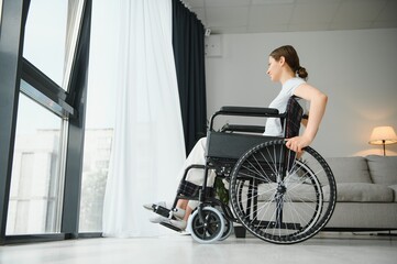 Young woman in wheelchair at home in living room.