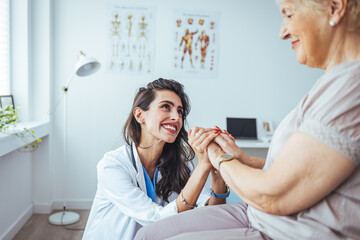 Friendly relationship between smiling caregiver in uniform and happy elderly woman. Supportive young nurse looking at senior woman. Young caring lovely caregiver and happy ward