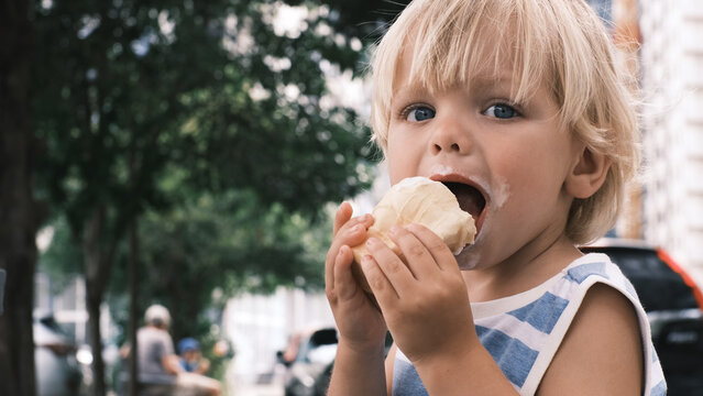 a small child eats white ice cream with great pleasure ice cream on face