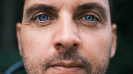 Close-up face of a young man with bright blue eyes looking seriously with curiosity