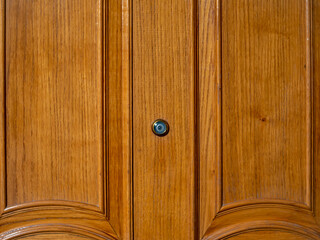 Door peephole on a wooden front door with a beautiful texture.