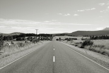 Straight road in South Island, New Zealand. Black and white vintage photo style.