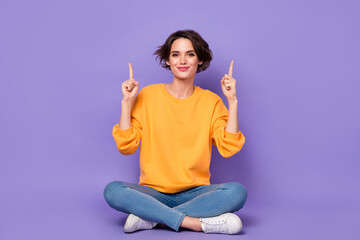 Portrait of attractive cheery girl sitting lotus pose showing copy space ad isolated over violet...