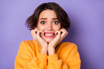Photo of scared young person arms touch cheeks biting finger nails isolated on violet color...