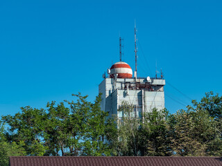 Station of cellular network antennas on a telecommunications mast on the roof of a building.
