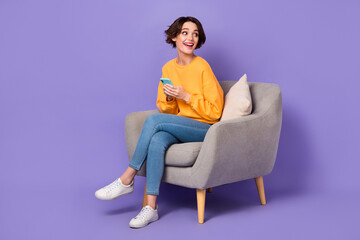 Portrait of attractive cheerful trendy girl sitting in chair using gadget looking copy space idea...