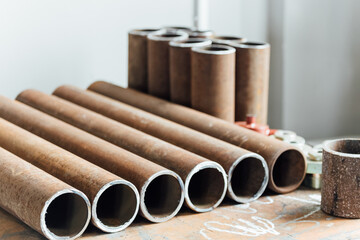 Round metal pipes of same diameter lie in row on workbench in industrial workshop. Manufacture and...