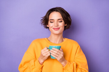 Portrait of attractive dreamy cheerful girl drinking herbal tea enjoying taste isolated over violet...