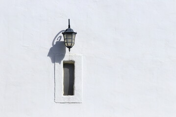 Old lantern on white wall, contrast of light and shadow 