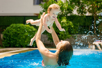 Happy child is having fun. The woman throws up and holds the baby up. Family happiness. Mom and...