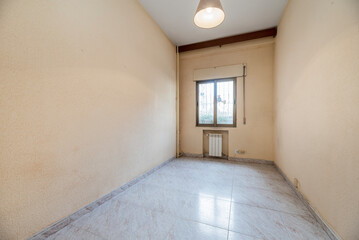 Empty room with cream and gotelet painted walls, gold aluminum windows and radiator below
