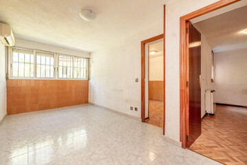 Empty room with access doors to other rooms with ceramic floors and a wall with brown tiles