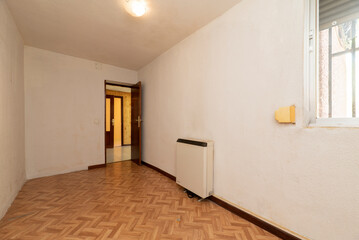 Empty room with oak parquet floor and wood carpentry on doors and heat accumulator on the wall