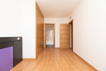 Empty room with oak parquet floor, plain white painted walls and oak joinery on doors and built-in wardrobe