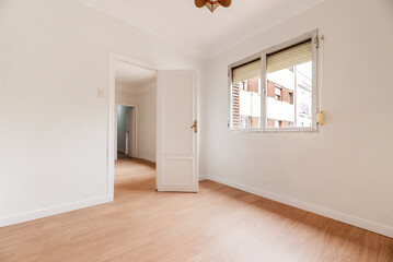 Empty living room with white painted walls with aluminum window, white carpentry, doors and lamps and light oak floor