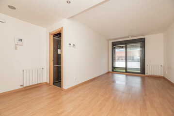 Empty living room with aluminum radiators, exit to a terrace with black aluminum sliding doors and...