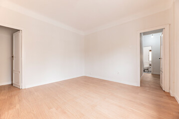 Fototapeta na wymiar Empty room with oak parquet floor, plain white painted walls and white woodwork and bathroom in another room