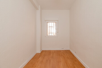 Small empty room with light wooden floors, white carpentry wood and white aluminum window