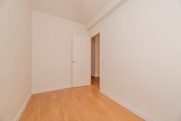Small empty room with light wood flooring, white woodwork and white wood door