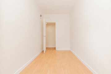 Empty room with white wooden doors and light wooden floor.