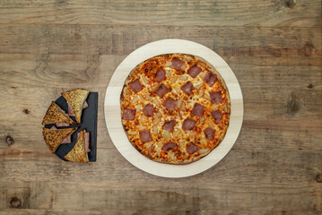Hawaiian pizza with toppings with ham on wooden table