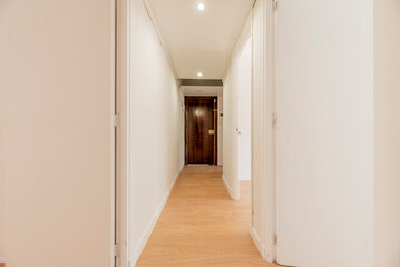 Long hallway of an empty residential home with oak floorboards and plain white painted walls