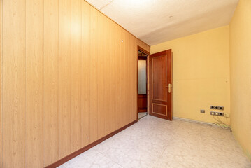 Empty room with wall covered in wood-like PVC tongue-and-groove and ceramic tile floors