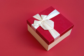 Top view of beautiful red gift box with satin light ribbon on red background. A gift for Christmas, New Year or a romantic Valentine's Day. Copy space for text.