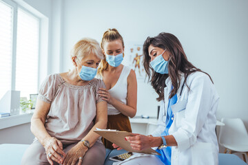 Senior woman and adult daughter with female doctor. Professional smiling doctor meeting a senior...