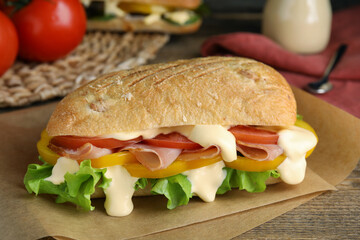 Delicious sandwich with vegetables, ham and mayonnaise served on wooden table, closeup