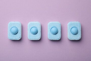 Water softener tablets on violet background, flat lay