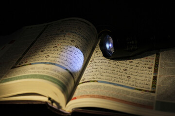 Quran close up in the dark room with low light and light from flashlight