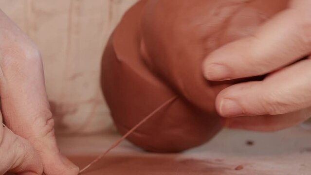Stoneware pottery clay cut with string by female hands.