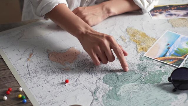 Tourist vacation planning with help world map with tourist accessories around. Young woman pointing finger route from India to Nepal world map. Tourist looks at world map. Near markers for waypoints
