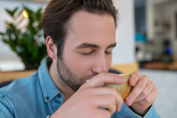 Man drinking coffee with closed eyes indoors