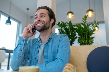 Man talking on smartphone sitting indoors during day