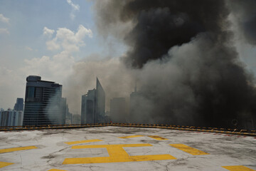 Manila, Philippines - July 11, 2013: large gray smoke reaches the top of a tall building with a...
