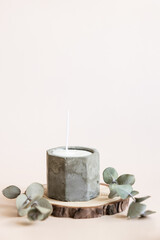 Obraz na płótnie Canvas Handmade candles from paraffin and soy wax in concrete plaster candlestick with wooden wick and dry herbal isolated on pastel beige background. Copy space