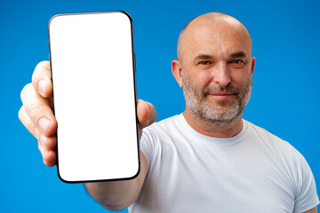 Middle-aged man showing blank smartphone screen with copy space against blue background