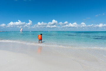 A child plays by the sea at a tropical beach in Isla Mujeres Mexico, during school vacations