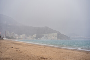 Fototapeta premium Dark storm clouds above the sea. Rocks, waves and water splashes close-up. Fickle weather, climate themes. Nature, tourism, cruise, recreation