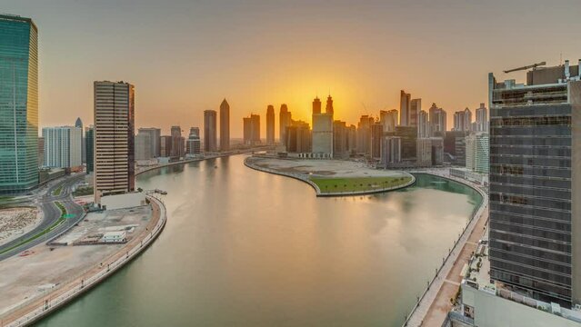 Sunset cityscape of skyscrapers in Dubai Business Bay with water canal aerial panoramic timelapse. Modern skyline with towers and waterfront. A center of international business