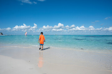 A child playing on the tropical beach in Isla Mujeres by the sea during summer vacation in Mexico