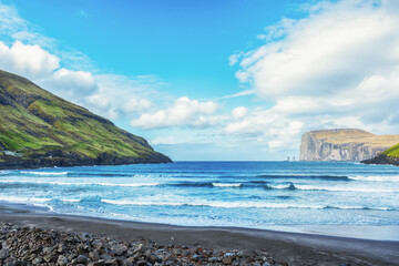 Fototapeta na wymiar Risin and Kellingin rocks. Sea bay, among beautiful mountains, and beautiful clouds in the blue sky.Tijornuvik bay on Streymoy island. Faroe Islands. Denmark. Europe. Landscapes.