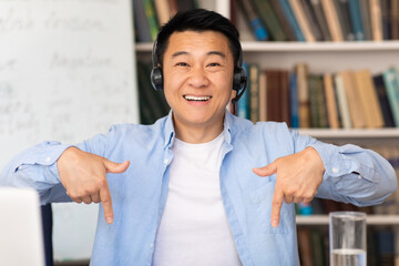 Happy Asian Teacher Man Wearing Headset In Modern Library