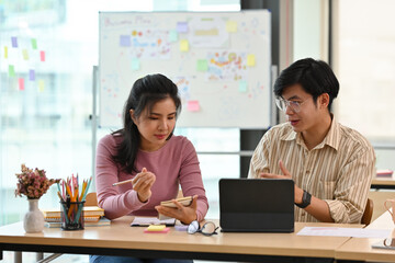 Obraz premium A portrait of Asian businesspeople sitting in an office, working together on a tablet and having a conversation, for business and technology concept.