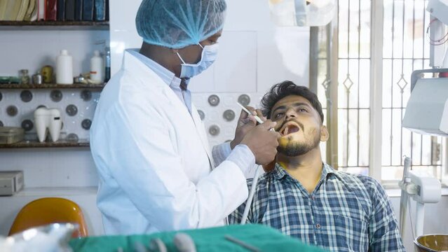 patient with dental doctor or dentist at hosptial looking at camera while treating - concept of oral care, diagnosis and professional occupation