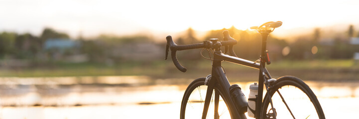 Road bike parked on a beautiful road sunset, warm light with copy space.