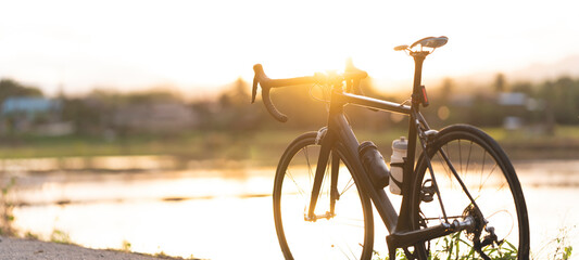 Rennrad geparkt auf einem schönen Straßensonnenuntergang, warmes Licht mit Kopienraum.