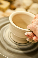 Töpfern an Drehscheibe mit weißem Ton, Hände formen eine Schale, Keramiker und Töpfer